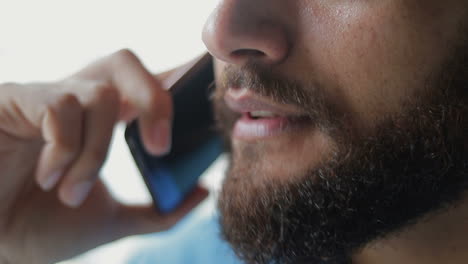 Close-up-shot-of-smiling-bearded-man-talking-on-smartphone.